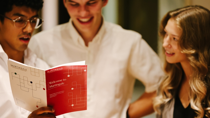 A photo of 3 students reading a booklet entitled 'Welcome to Martingale'.