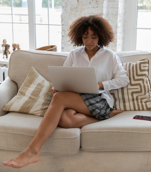 young African American lady sitting on a sofa working on her laptop