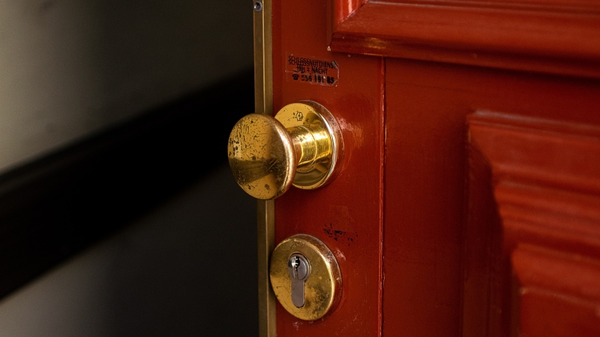 A red door with a brass handle, opening slightly