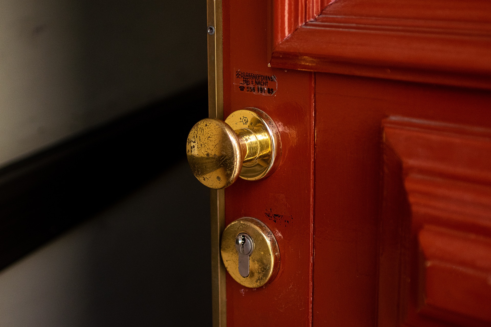 A red door with a brass handle, opening slightly